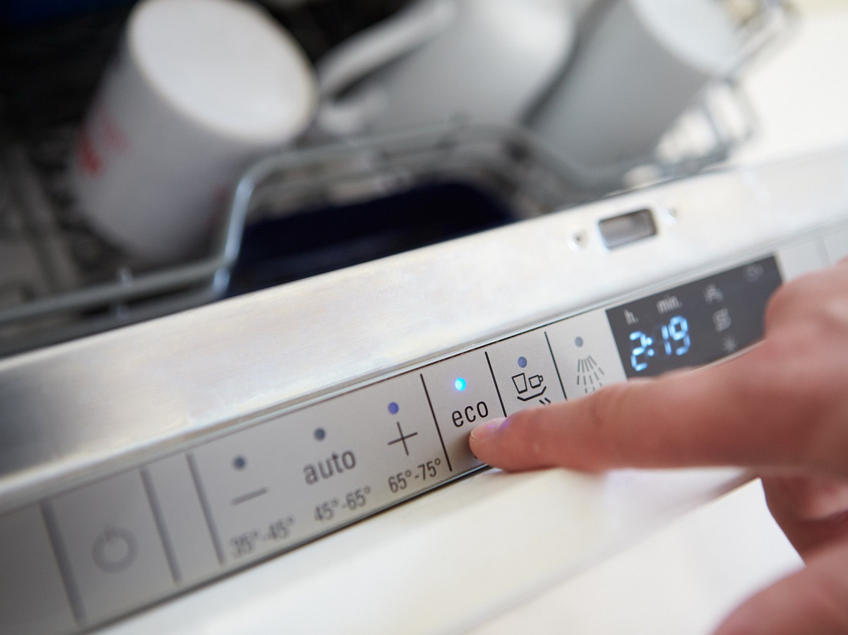 Close Up Of Man Setting Economy Cycle On Dishwasher Appliance